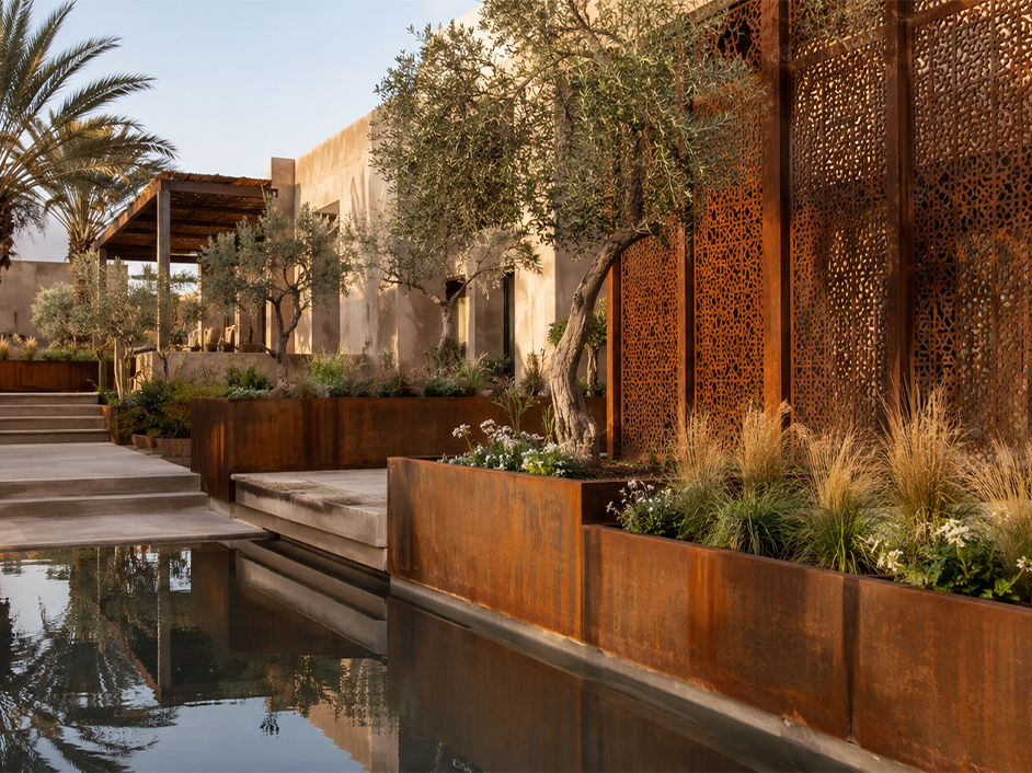 Aménagement paysager en Acier Corten Maroc avec jardinières rectangulaires et panneaux décoratifs ajourés dans un jardin contemporain.