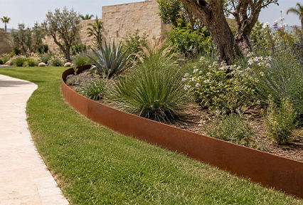 Bordure courbe en Acier Corten Maroc séparant une pelouse et un massif végétalisé dans un jardin paysager.