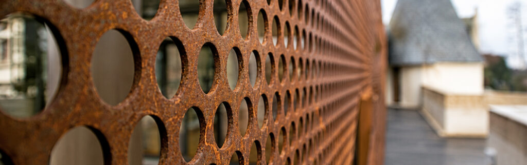 Détail d’un panneau perforé en Acier Corten Maroc utilisé comme habillage de façade architecturale contemporaine.