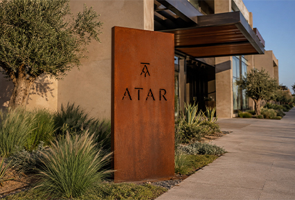 Totem signalétique vertical en Acier Corten Maroc avec lettrage découpé installé à l’entrée d’un bâtiment contemporain.