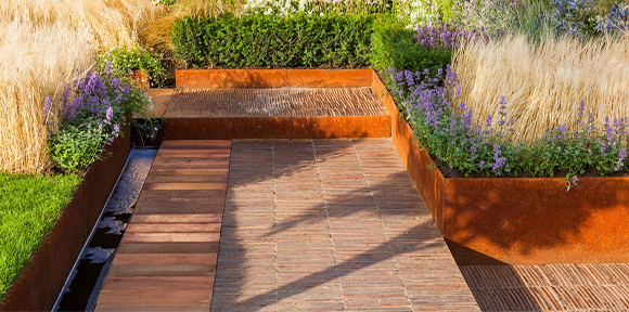 Aménagement paysager final avec bordures, jardinières et banc réalisé dans le cadre de la Fabrication acier Corten sur mesure.