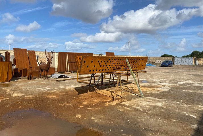 Atelier de Fabrication acier Corten avec panneaux perforés, structures métalliques et sculptures en cours de préparation.