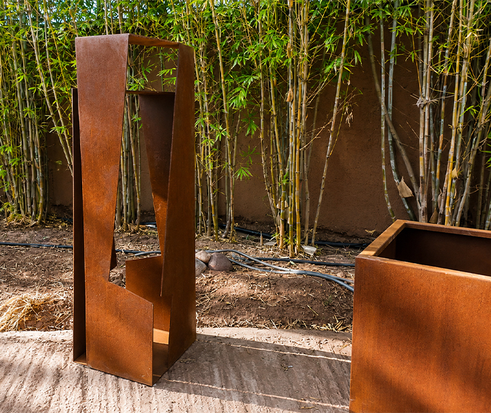 Fontaine décorative verticale faisant partie de Projets en acier Corten, installée dans un jardin contemporain avec végétation.