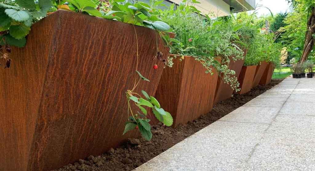 Jardinières sur mesure intégrées à des Projets en acier Corten le long d’une allée végétalisée contemporaine.