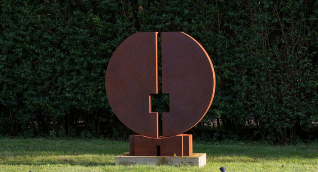 Sculpture géométrique circulaire intégrée à des Projets en acier Corten dans un jardin paysager contemporain.