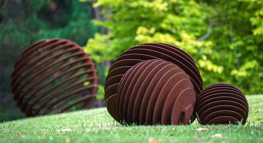 Sculptures sphériques décoratives intégrées à des Projets en acier Corten dans un jardin paysager contemporain.