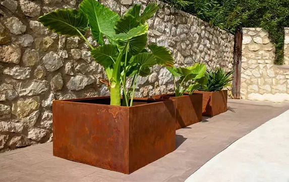 Jardinières sur mesure dans une villa faisant partie de nos Réalisations en acier Corten, installées devant un mur en pierre naturelle.